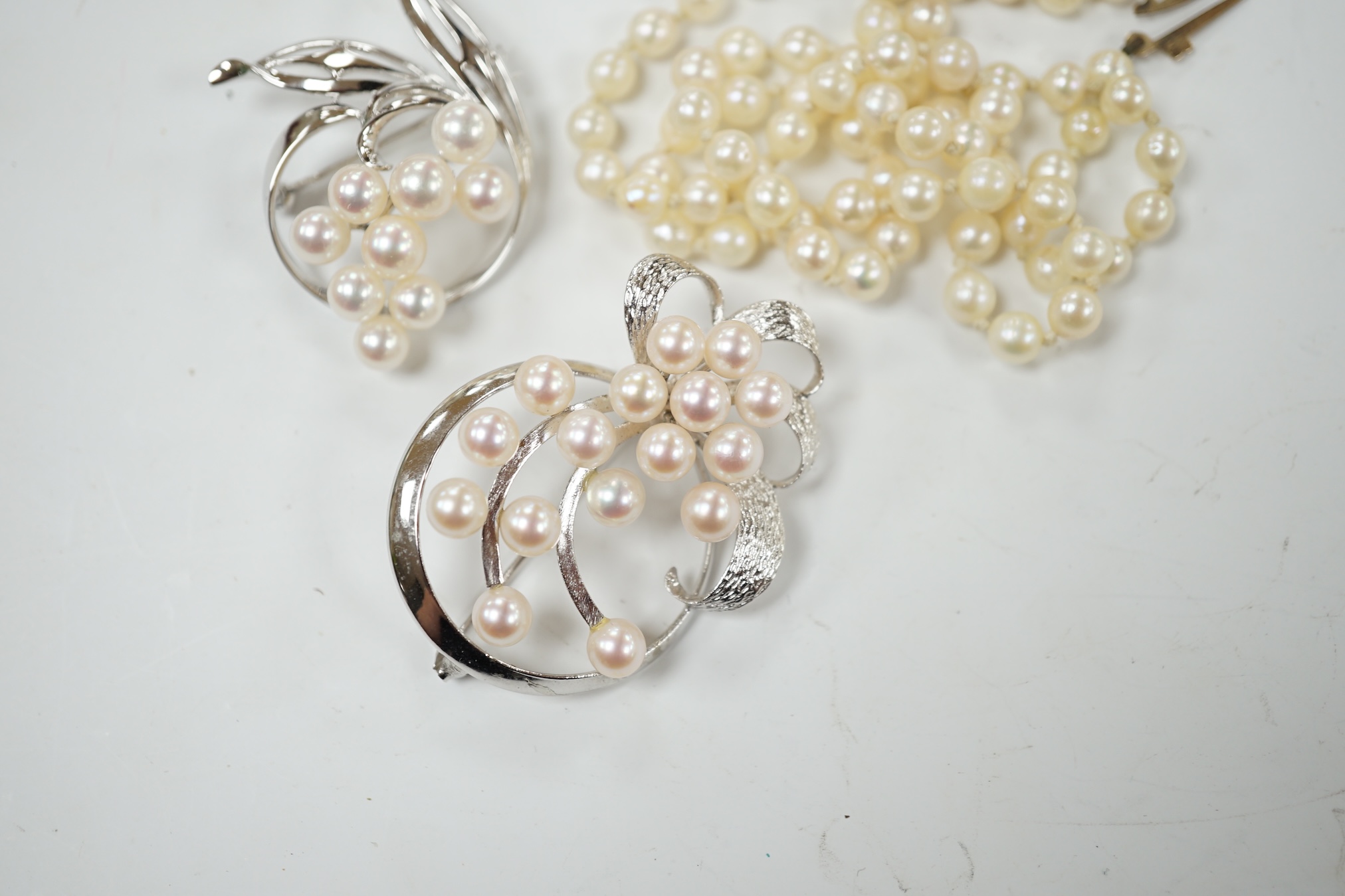 A Mikimoto white metal and cultured pearl cluster set spray brooch, 41mm, one other white metal and cultured pearl cluster set spray brooch, stamped 'silver' and a single strand cultured pearl necklace with a 9ct gold cl